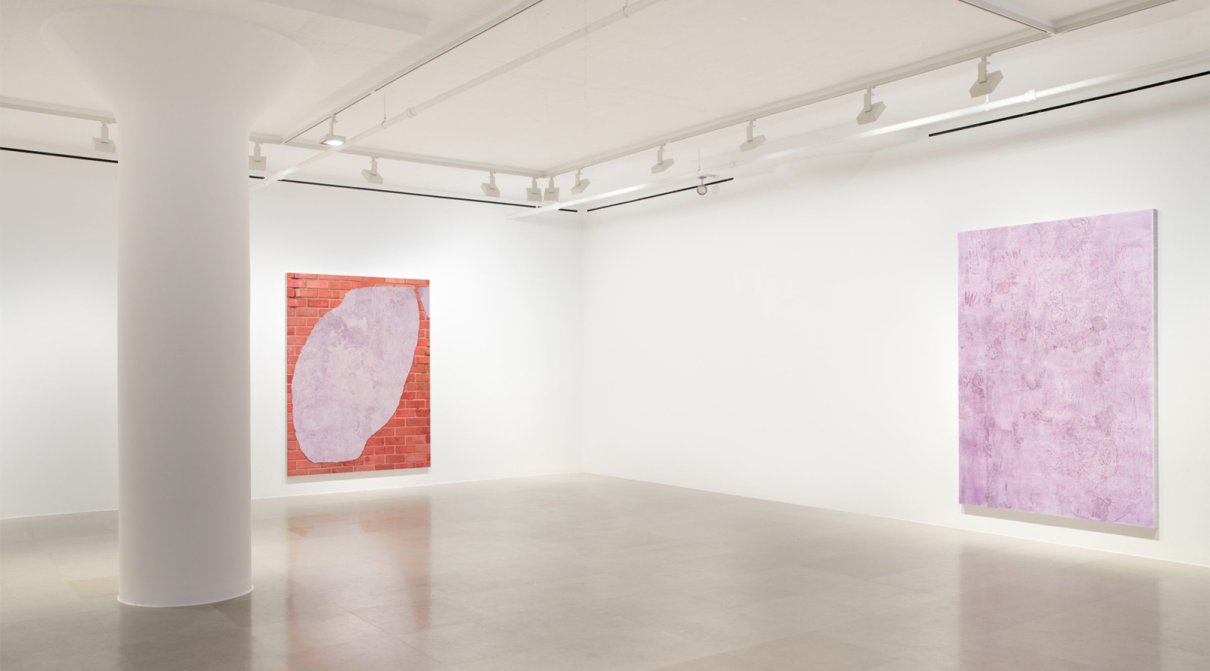 The corner of a gallery with a painting on each wall, on the right is a lavender monochrome with marks and drawings scratched into the surface,  on the left the painting shows a brick wall overlaid with a swath of lavender with marks and drawings scratched into the surface.
